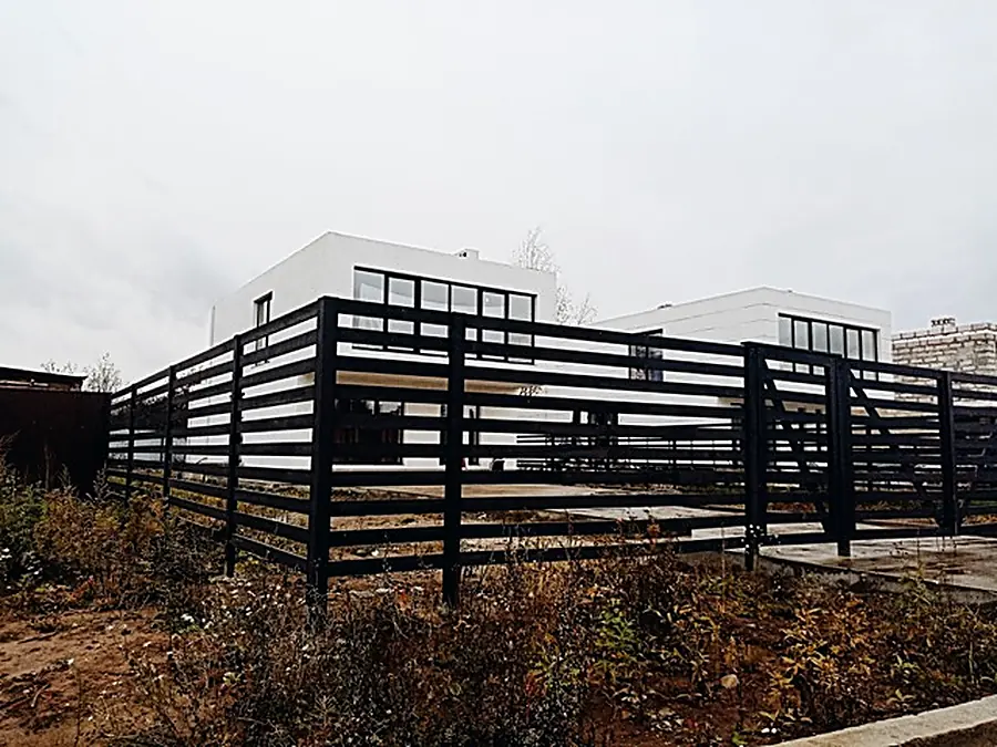 Home under construction behind a black horizontal slat fence